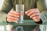 Close up of man holding a pill and glass of water