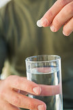 Close up of a man holding glass of water and pill