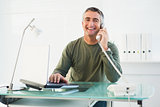 Smiling man on the phone using laptop