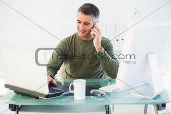 Happy man phoning and using laptop
