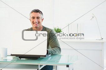 Happy man using his laptop at desk