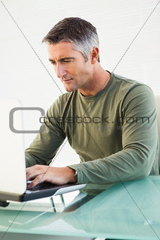 Concentrated casual man using laptop