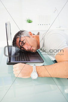 Man with glasses sleeping on his laptop