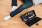 Mid section of a man lying with tools box