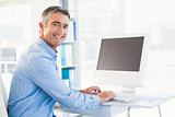 Smiling man typing on keyboard and looking at camera