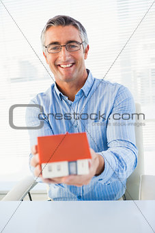 Happy man with glasses showing model house