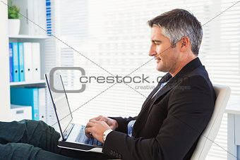 Cheerful businessman using laptop and relaxing