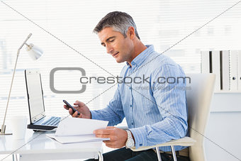 Man using mobile phone and looking in notebook