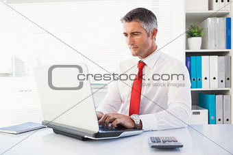 Cheerful businessman typing on laptop