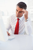 Concentrated businessman using computer and thinking