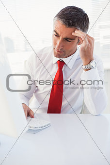 Concentrated businessman using computer and thinking