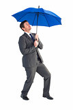 Businessman sheltering under blue umbrella