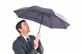 Businessman sheltering under black umbrella