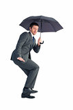 Businessman sheltering under black umbrella