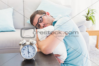 Bored man on the table beside alarm clock