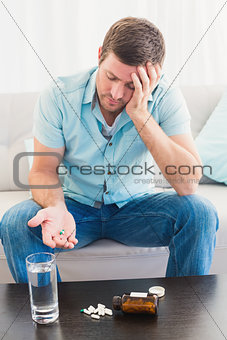 Hungover man with his medicine laid out on coffee table
