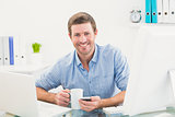 Smiling businessman holding mug and phone