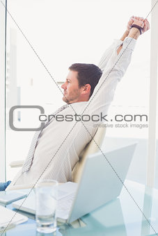 A businessman stretching in swivel chair