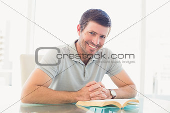 Casual businessman sitting at desk reading a book