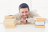 Smiling casual businessman with books at his desk