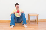 Casual man sitting on floor holding a mug at home