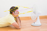 Man lying on floor looking at fan at home