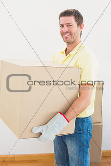 Smiling man carrying cardboard moving boxes at home