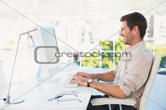 Smiling businessman using his computer at his desk