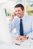 Smiling businessman phoning at his desk