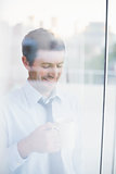Smiling businessman holding mug seen through window