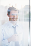 Smiling businessman holding mug looking out the window