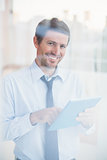Smiling businessman using tablet looking out the window