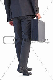 Rear view of businessman holding briefcase walking