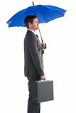 Serious businessman holding his umbrella and briefcase