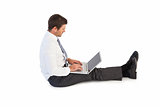 Businessman sitting on the floor typing on his laptop