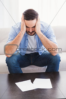 Upset man sitting head in hands on couch