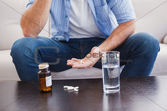 Man taking his pills on couch