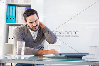 Frowning handsome businessman having neck pain