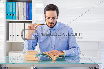 Focused businessman reading book at desk