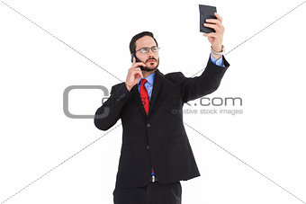 Businessman holding calculator while talking on phone
