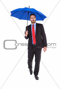 Unsmiling businessman holding an umbrella