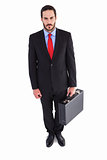Serious handsome businessman holding briefcase