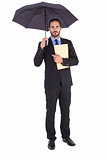 Serious businessman holding a file under umbrella