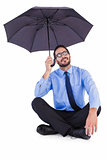 Businesswoman in suit sitting while holding umbrella