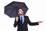 Businesswoman holding umbrella while testing if it rains