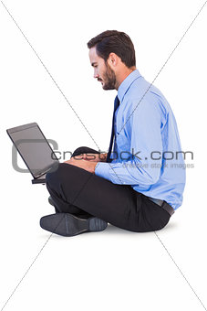Businessman sitting on the floor using his laptop