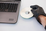 Burglar hacking and putting a cd-rom in laptop