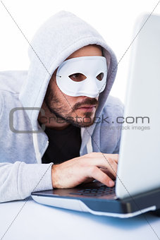 Man wearing mask while hacking into laptop