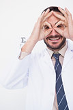Smiling doctor forming eyeglasses with his hands