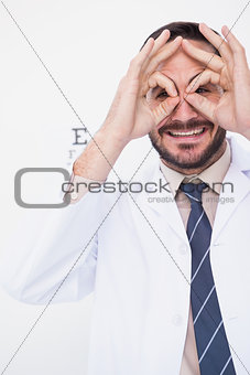 Smiling doctor forming eyeglasses with his hands